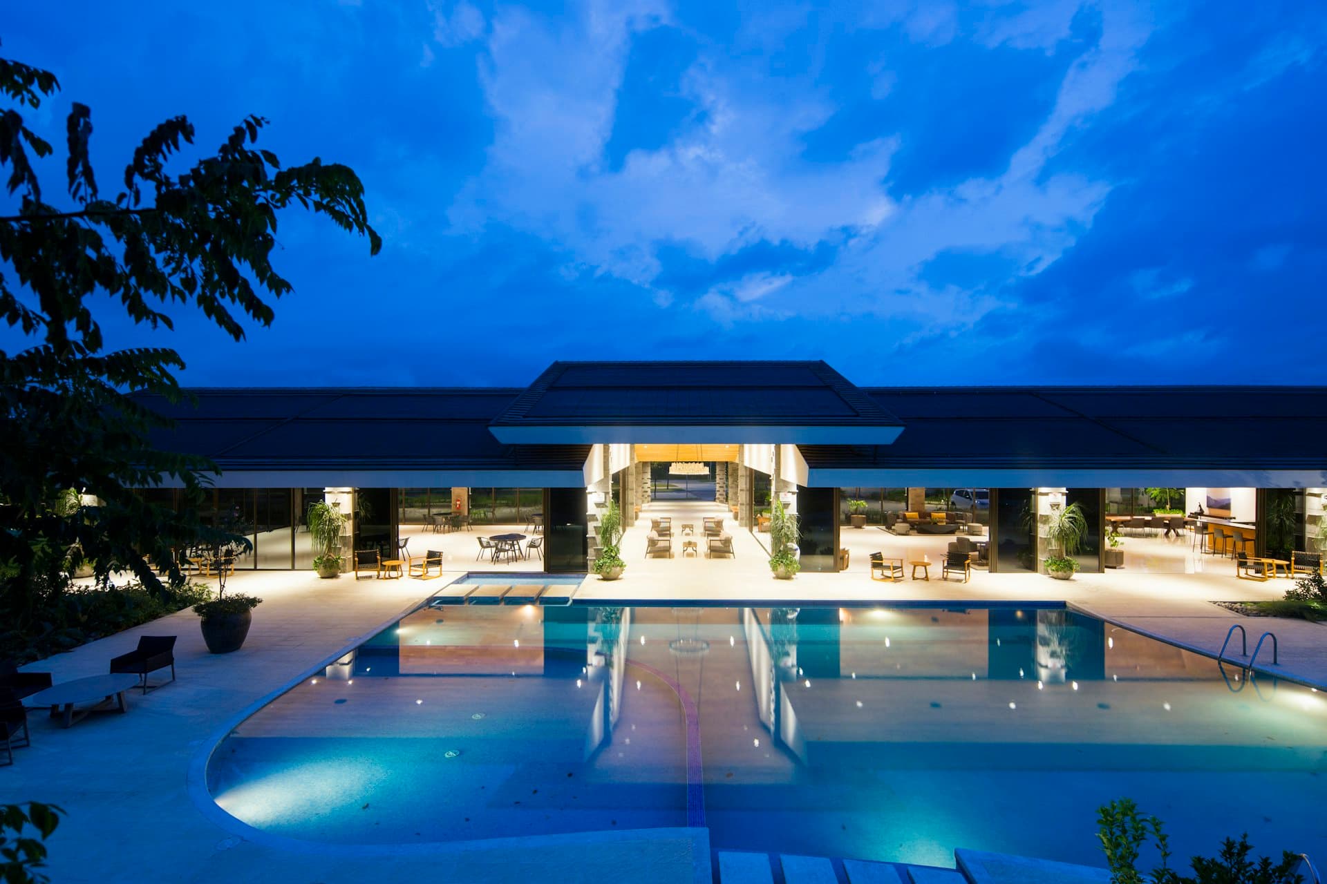 A resort pool and lounge glowing at dusk