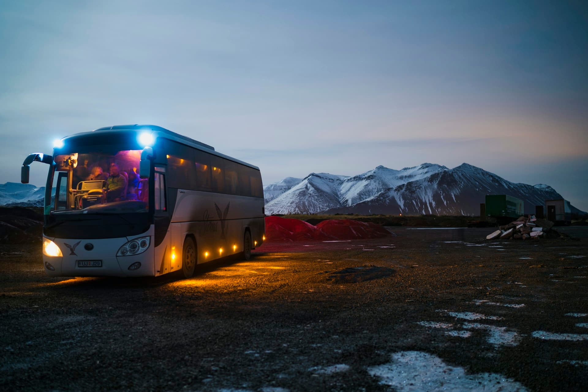 A coach at dusk below snow-capped mountains